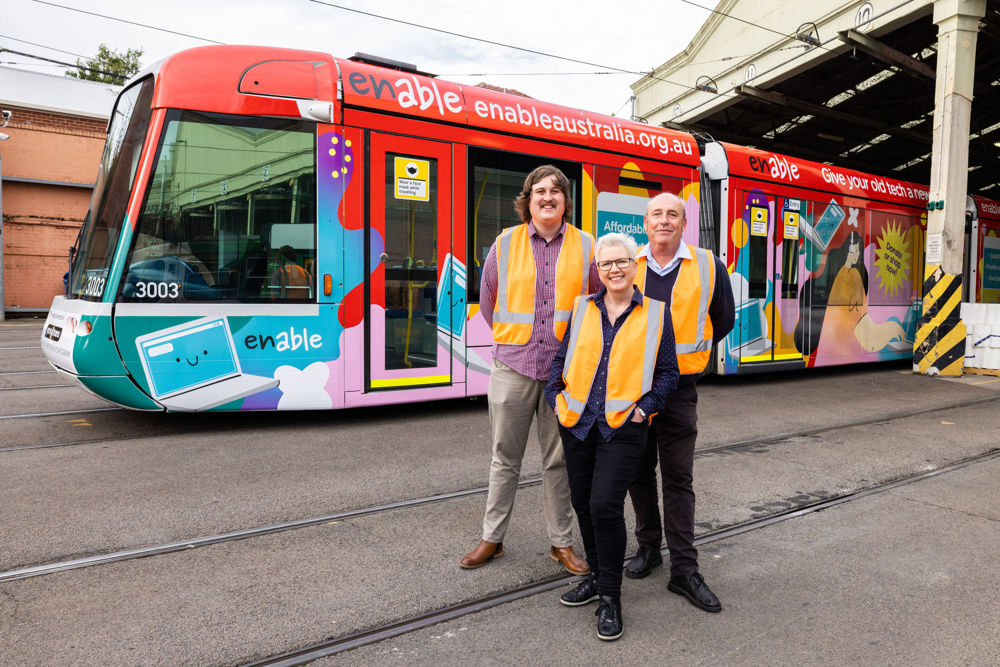 Photo: Enable Australia's vibrant tram and members of the Enable Australia team and board.