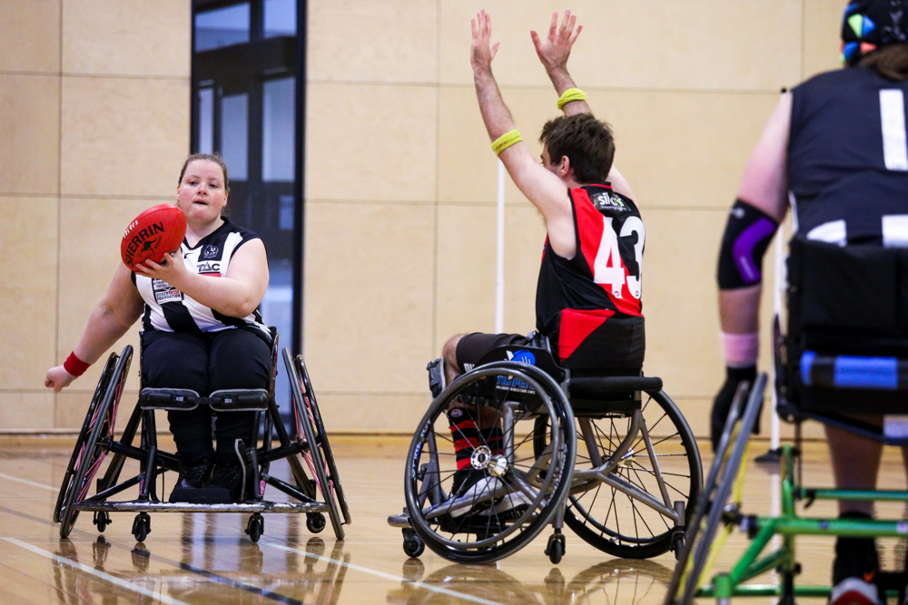 Female AFL player in wheelchair passing ball