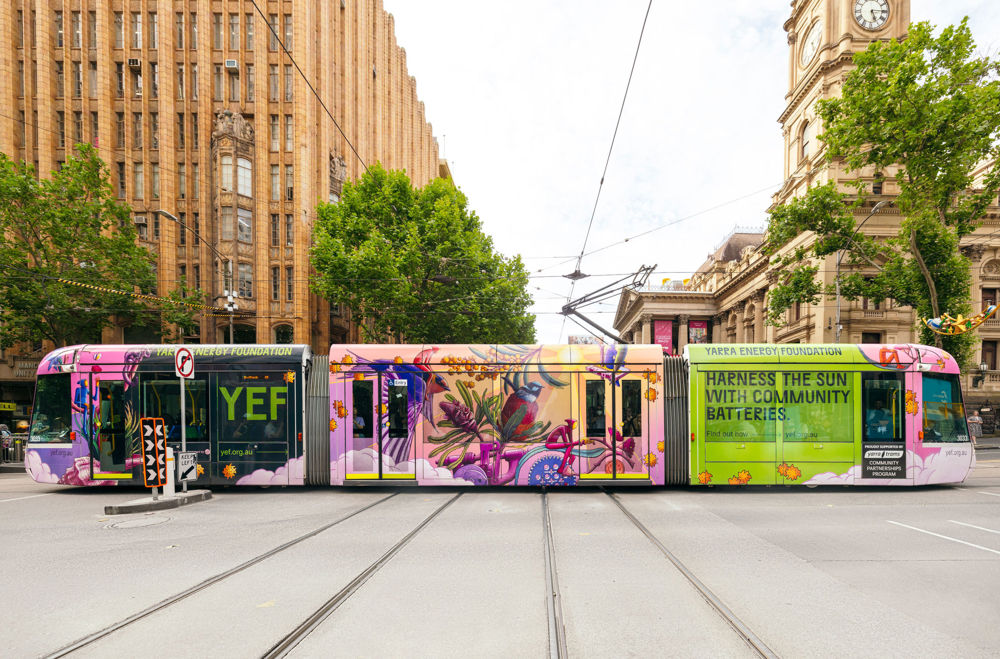 Photo of a C1 tram wrapped in a design from Yarra Energy Foundation, including the wording 'Harness the Sun with community Batteries' and artwork of birds and plants