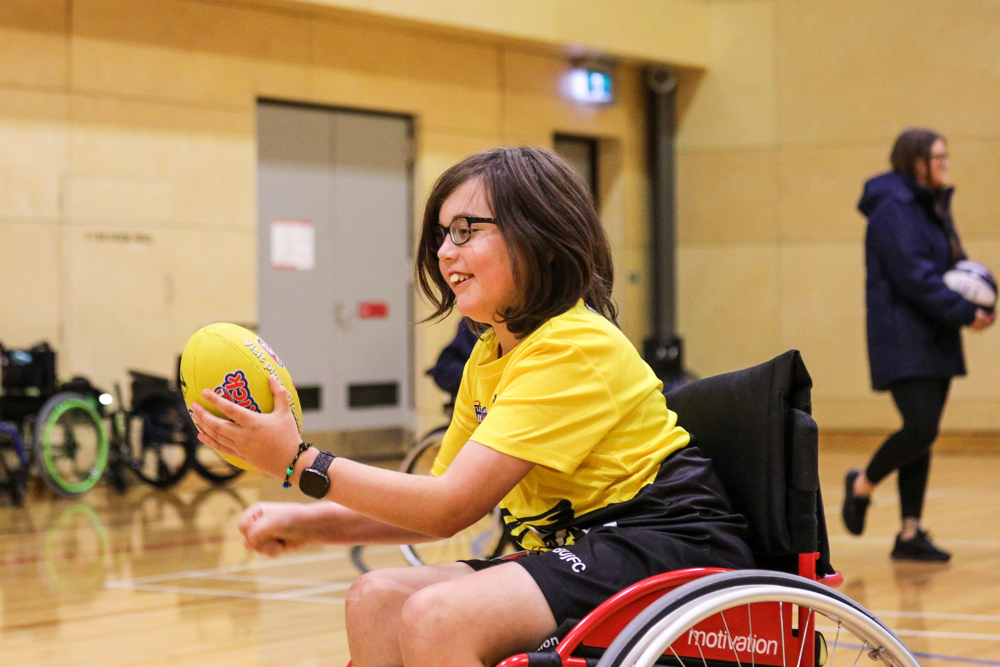 Young AFL Auskick girl passing ball